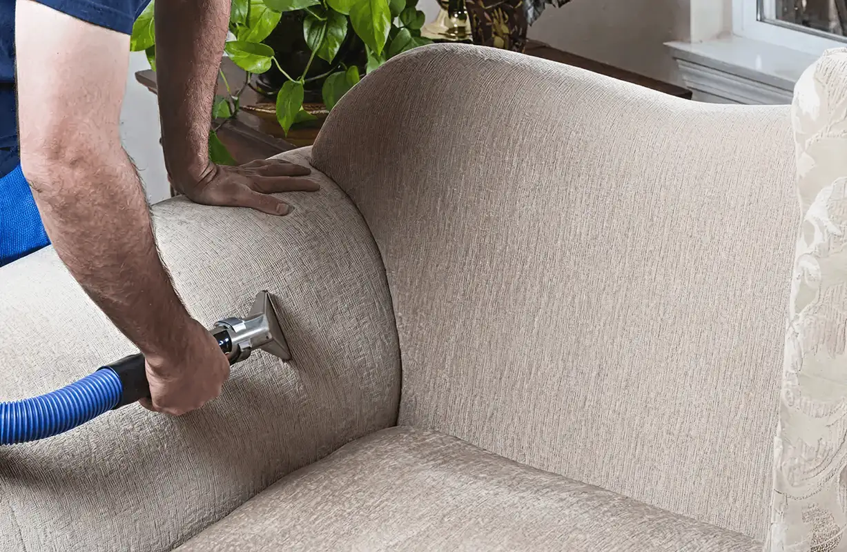 Professional upholstery cleaner deep-cleaning a fabric sofa with a handheld extraction tool and hose, Chandler, AZ.